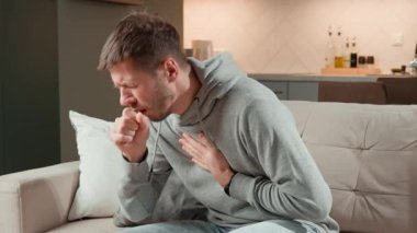 Evdeki kanepede oturan hasta bir adam, öksürüyor, göğüs ağrısı ve solunum sorunları, grip, astım ya da bronşit belirtileri gösteriyor. Hastalık, enfeksiyon ve hastalık konsepti