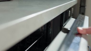 Bulaşık makinesinin açık kapılı kontrol panelinde elle başlatma düğmesine bas. Kadın modern ev aletleri kullanıyor, bulaşık makinesinde kirli bulaşıkları yıkamak için otomatik programı seçiyor.