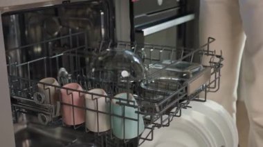 Bulaşık makinesinin içine temiz bulaşık, bardak ve bardakları yerleştirin. Modern mutfak aletleri. Günlük ev işleri