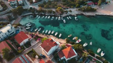 Kırmızı çatılı evleri, turkuaz suları ve kıyı boyunca tekneleri olan kıyı köyünün havadan görünüşü. Hırvatistan 'ın Adriyatik Denizi kıyısındaki Rogoznica kentinin panoraması. Yaz tatili kavramı