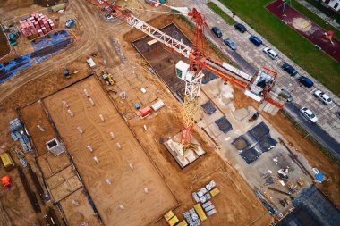İnşaat alanının vinçlerle, vakıflarla ve inşaat malzemeleriyle hava görüntüsü. İkamet binası yapım aşamasında. Küçük kasabada yeni gelişmeler