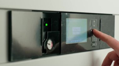 Isı pompası kontrol panelindeki ısıyı dijital ekranla ayarlayan kişiye yakın çekim. Modern sistemlerde ev ısıtma ve enerji verimliliği kavramı