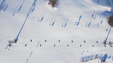 Kayakçılarla, snowboardcularla ve kayak pistlerindeki iskemlelerle kış tatil köyünün hava manzarası. Kış sporları ve açık hava aktiviteleri