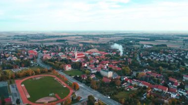Sonbahar mevsiminde tarlalar ve ormanlarla çevrili güzel küçük bir kasabanın hava manzarası. Polonya 'daki köyün kuş bakışı görüntüsü. Kenar mahallelerdeki konut binalarının manzarası