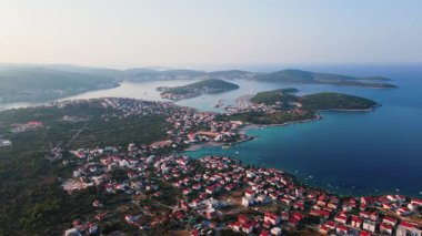 Kırmızı çatılı evleri, turkuaz denizi ve arka planda küçük adaları olan kıyı kasabasının havadan görünüşü. Adriyatik denizinde renkli binaları olan turistik bir şehir. Hırvatistan 'ın Rogoznica kasabasının panoramik manzarası