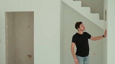 Siyah gömlekli adam yenileme sırasında satın alınan dairenin içini inceliyor. Parlak, modern bir iç mekanda yürüyen ve etrafa bakan biri. Yeni ev ve gayrimenkul alma kavramı