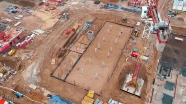 İnşaat alanının vinçlerle, vakıflarla ve inşaat malzemeleriyle hava görüntüsü. İkamet binası yapım aşamasında. Küçük kasabada yeni gelişmeler