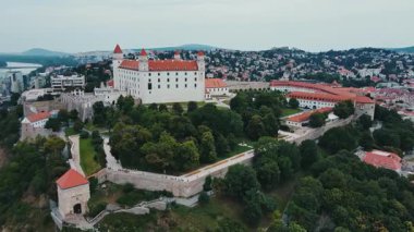 Bratislava Kalesi 'nin havadan görünüşü, Slovakya' nın tarihi simgesi. Tuna Nehri kıyısındaki eski kale, yeşil bahçeler ve şehir tahkimatlarıyla çevrili.