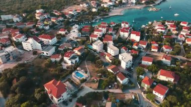 Akdeniz kıyı kasabasının kırmızı çatılı evleri, yemyeşil ve deniz plajları olan havadan görünüşü. Yaz tatili için geleneksel binaları olan köyün panoramik manzarası. Hırvatistan 'ın Rogoznica kentinin manzarası