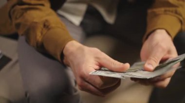 Evde dolar sayan biri var. Kanepede oturan adam, elinde nakit para tutuyor. Para, tasarruf ve mali planlama kavramı