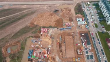 İnşaat alanının vinçlerle, vakıflarla ve inşaat malzemeleriyle hava görüntüsü. İkamet binası yapım aşamasında. Küçük kasabada yeni gelişmeler