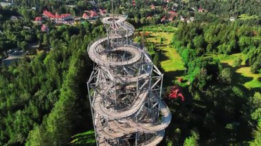 Polonya 'nın Sweradow Zdroj kentindeki Gökyüzü Yürüyüşü spiral gözlem kulesinin havadan görünüşü yeşil ormanlarla çevrili. Çevredeki dağların nefes kesici panoramik manzaralı popüler turistik cazibesi