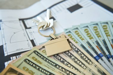 Evin anahtarları ve mimari plandaki dolar banknotları, gayrimenkul yatırımları. Ev satın alma, yenileme bütçesi veya ipotek planlama kavramı