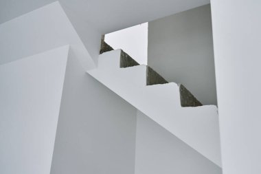 Modern minimalist iç mekanda tamamlanmamış beton merdiven. Ham inşaat elementleri ve beyaz duvarları olan yeni bir daire. Bina onarım altında