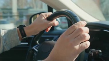 Sürücü erkek ellerin direksiyonu sıkıca kavrarken yakın plan çekimleri. Dışarıda sokak penceresi olan bir adam şehirde araba kullanıyor. Seyahat, ulaşım ve yol güvenliği kavramı