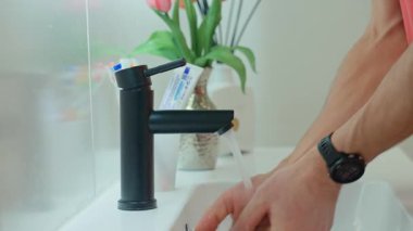 Modern banyoda yüzünü suyla yıkayan bir adam, sabah rutini. Hijyen ve kişisel bakım kavramı