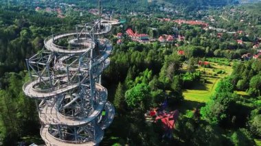 Polonya 'nın Sweradow Zdroj kentindeki Gökyüzü Yürüyüşü spiral gözlem kulesinin havadan görünüşü yeşil ormanlarla çevrili. Çevredeki dağların nefes kesici panoramik manzaralı popüler turistik cazibesi