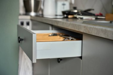 Düzenlenmiş çatal bıçak setiyle mutfak çekmecesi ve ahşap düzenleyicide mutfak gereçleri. Çağdaş mutfak dolabı. Ev organizasyonu ve mutfak verimliliği kavramı