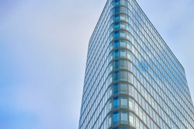 Gökyüzüne karşı kıvrımlı cepheli modern gökdelen. Dışarısı cam kaplı, yüksek katlı bir ofis binası. Çağdaş mimari kavramı