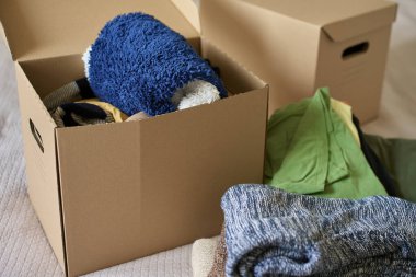 Yatakta bağışlanmış kıyafetlerle dolu açık bağış kutusu. Geri dönüşüm için kullanılmış giysilerle dolu bir karton kutu. Sadaka, nezaket ve sosyal sorumluluk kavramı