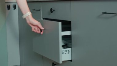 Kişi, ahşap çatal bıçak tepsisindeki çeşitli çatal bıçaklarla mutfak çekmecesini açar. Kadın mutfak dolabını açıyor. Ev organizasyonu ve işlevsellik kavramı