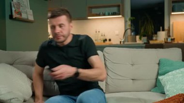 Adam elinde uzaktan kumandayla kanepede oturuyor. Kanepede dinlenen ve televizyon izleyen biri. Rahatlama, boş zaman ve ev eğlencesi kavramı