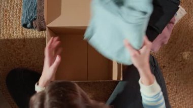 Kadınlar bağış kutusunu, üzerinde giysileri olan yataklara koyar, hayır işleri için eşyalar düzenler. Geri dönüşüm ya da ikinci el kıyafetlerle dolu bir karton kutu. Gönüllü olma, yardım ve sosyal sorumluluk kavramı