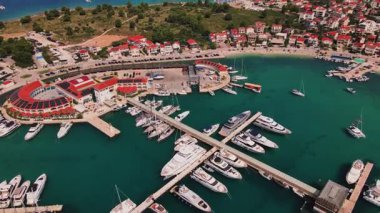İskeleler boyunca rıhtımda liman manzaralı lüks yatlar. Liman, yeşil kıyı şeridinde yelkenli teknelerle dolu. Yaz seyahati, tatil ve deniz faaliyetleri kavramı