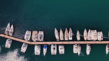 Yat ve teknelerin marina iskelesi boyunca havadan görüntüsü. Yaz seyahati, tatil ve deniz faaliyetleri kavramı