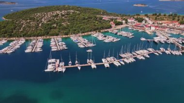İskeleler boyunca rıhtımda liman manzaralı lüks yatlar. Liman, yeşil kıyı şeridinde yelkenli teknelerle dolu. Yaz seyahati, tatil ve deniz faaliyetleri kavramı