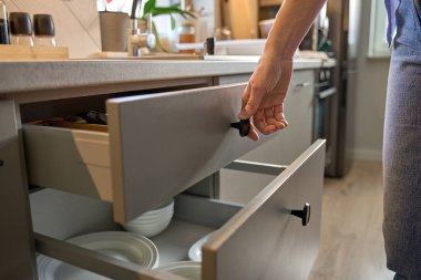 Kişi, ahşap çatal bıçak tepsisindeki çeşitli çatal bıçaklarla mutfak çekmecesini açar. Kadın mutfak dolabını açıyor. Ev organizasyonu ve işlevsellik kavramı