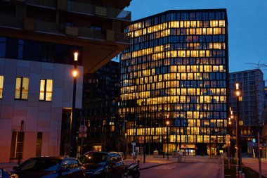 Geceleri parlayan pencereli modern ofis binası var. Şirkette gece geç saatlere kadar çalışıyorum. İş etkinliği kavramı, şirket hayatı ve modern mimari