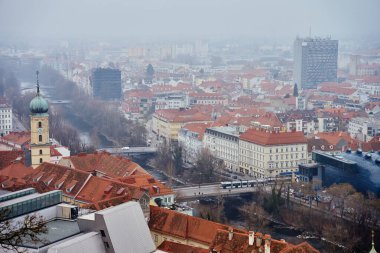 Sisli bir günde Graz şehri manzarası. Graz, Avusturya 'nın tarihi mimarisi ile panoramik manzarası. Avrupa 'da kırmızı çatılı binaları olan sokaklar