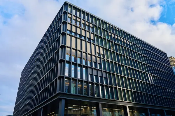 Cam ve metal cepheli modern ofis binası. Geometrik tasarımı ve yansıtıcı pencereleri olan yüksek katlı bir bina. Kentsel iş bölgesinde çağdaş mimari
