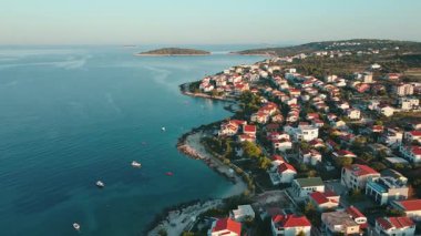 Sakin mavi kıyı şeridi boyunca geleneksel evleri olan kıyı köyünün havadan görünüşü. Adriyatik Denizi ve küçük bir kasabayla Akdeniz manzarası. Hırvatistan 'ın Rogoznica kentinin manzarası