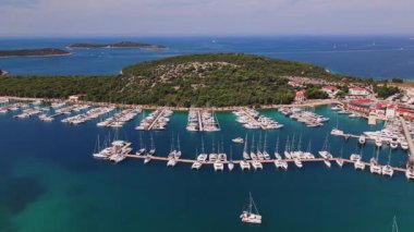 İskeleler boyunca rıhtımda liman manzaralı lüks yatlar. Liman, yeşil kıyı şeridinde yelkenli teknelerle dolu. Yaz seyahati, tatil ve deniz faaliyetleri kavramı