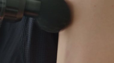 Masaj tabancasının kafa derisine bastırdığı yakın plan. Kas iyileşmesi ve gevşeme için perküsyon masaj aleti kullanılıyor.