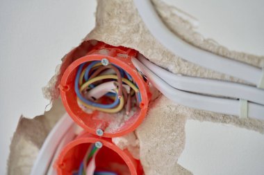 Tadilat sırasında elektrik tesisatı kurulumu. Duvara gömülü elektrik kablolarının olduğu plastik priz kutuları. Görünür elektrik kabloları ve soket tutacaklarıyla tamamlanmamış bir duvar.