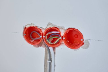 Tadilat sırasında elektrik tesisatı kurulumu. Duvara gömülü üç plastik elektrik kablosu. Görünür elektrik kabloları ve soket tutacaklarıyla tamamlanmamış bir duvar.