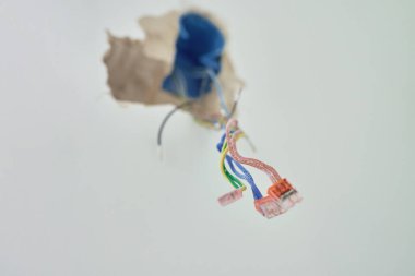 Renklendirme sırasında duvardan renkli kablolar sarkıyor. Elektrik kurulumu ve inşaatı kavramı