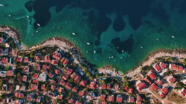 Kızıl çatıları ve turkuaz denizdeki tekneleri olan kıyı köyünün havadan görüntüsü. Hırvatistan 'ın Adriyatik Denizi kıyısındaki Rogoznica kentinin panoraması. Yaz tatili ve seyahat konsepti