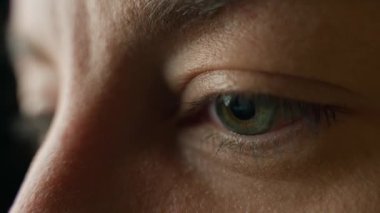 Karanlık odada televizyon izleyen insan gözünün yakın çekimi. Gözbebeklerinde ekran yansıması olan kadın göz.