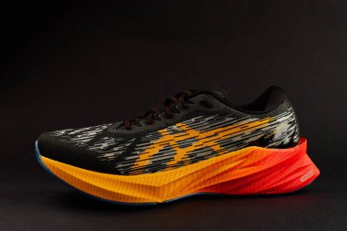 Modern Asics Novablast koyu arka planda koşu ayakkabıları. Canlı renk kontrastlı şık bir spor ayakkabısı spor ve spor için zarif bir tasarım. Wroclaw, Polonya - 6 Kasım 2024