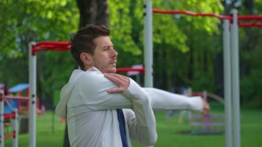 Spor giyimli bir adam yeşilliklerle çevrili açık hava spor salonunda esniyor. Atletik adam antrenmandan önce parkta ısınıyor. Zindelik, sağlıklı yaşam tarzı ve sağlık kavramı