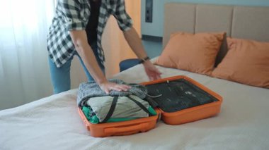 Yolculuktan önce turuncu bavulu kapatmaya çalışan bir adam. Erkek gezgin bir sürü giysi hazırlarken, seyahat için hazırlanırken zorlanır.