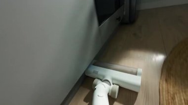 Mutfakta yerleri süpüren ve yuvarlak halı döşeyen kişinin görüntüsü. Evde elektrikli süpürge kullanmayı unutma. Günlük ev işi kavramı