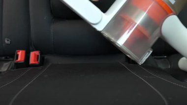 Kablosuz elektrikli süpürge, araba koltuğu döşemesini süpürüyor. Modern araba temizliği ve bakımı