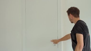 İşçi, balon seviyesiyle kapının dikey hizasını kontrol ediyor. Profesyonel iç kapı döşemesi. Ev yenilenmesi