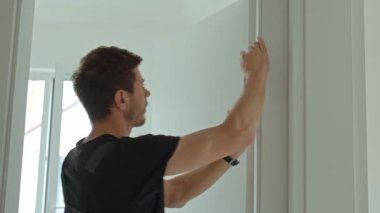 Yeni daireye kapı döşeyen bir adam. Tadilat sırasında kapı çerçevesini ayarlayan inşaat işçisi. Tamirci giriş kapısını kontrol ediyor.