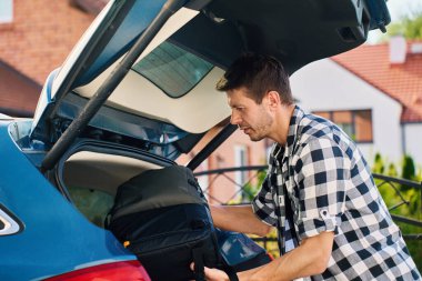 Yolculuk için bir adam sırt çantasını arabanın bagajına yüklüyor. Bagajları araca koyarak yolculuk için hazırlanıyoruz. Açık hava yolculuğu kavramı